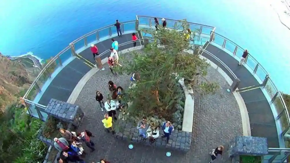 Aerial view of circular viewpoint platform with visitors and blue sea