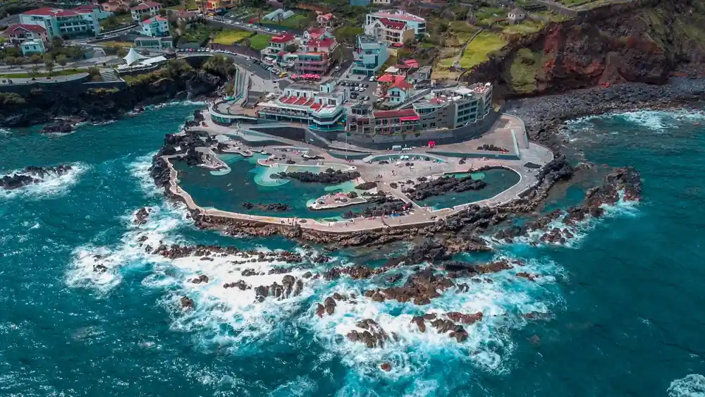 Aerial view of coastal resort with curved pools and rocky peninsula