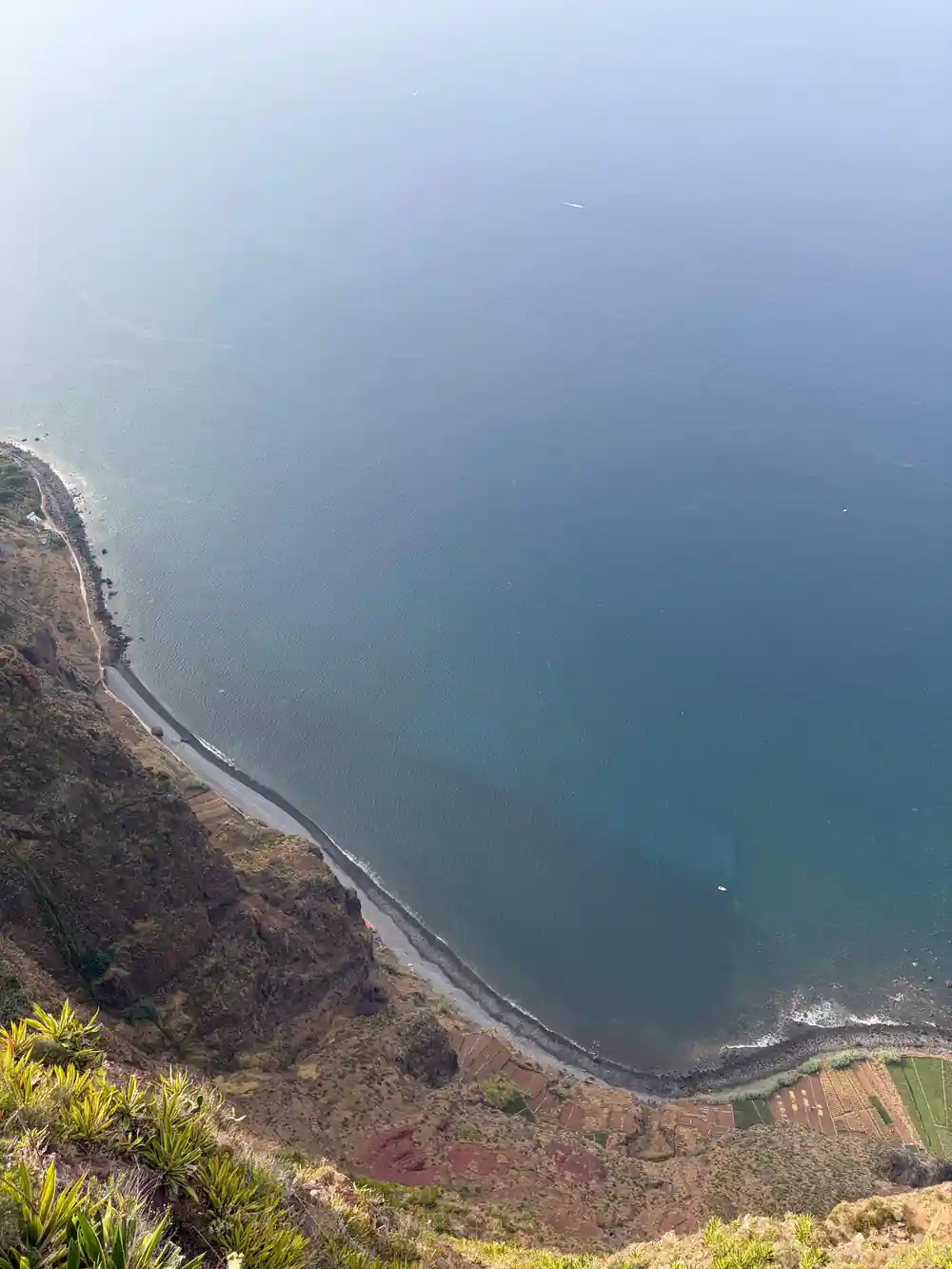 Aerial view of curved coastal beach and rocky shoreline