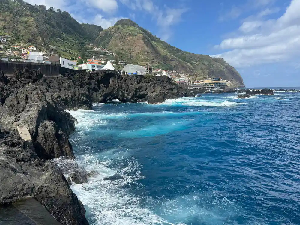 Coastal village on volcanic cliff with turquoise sea