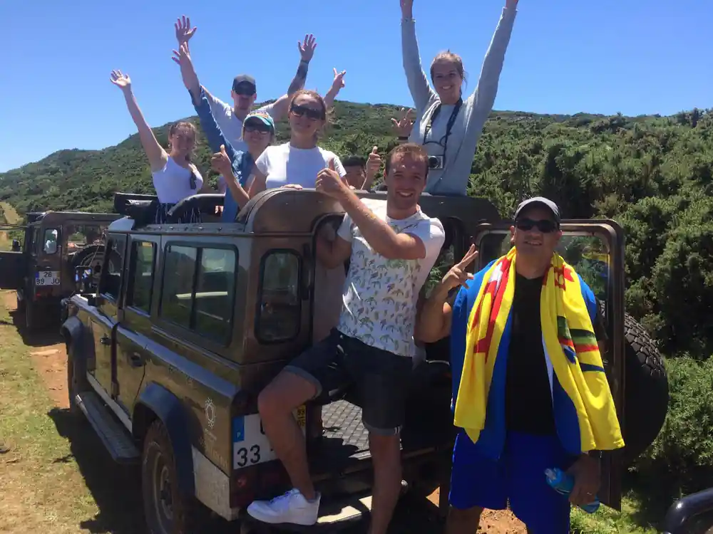 Group of people celebrating on vehicles with forested hillside background