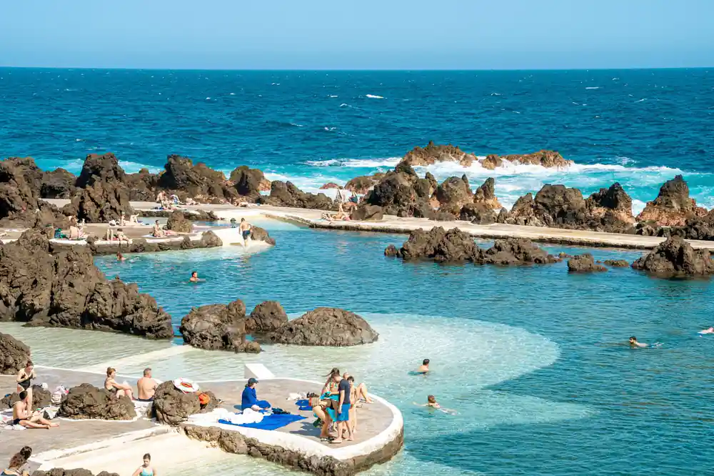 Natural rock pools and shallow waters with swimmers on rocky coast