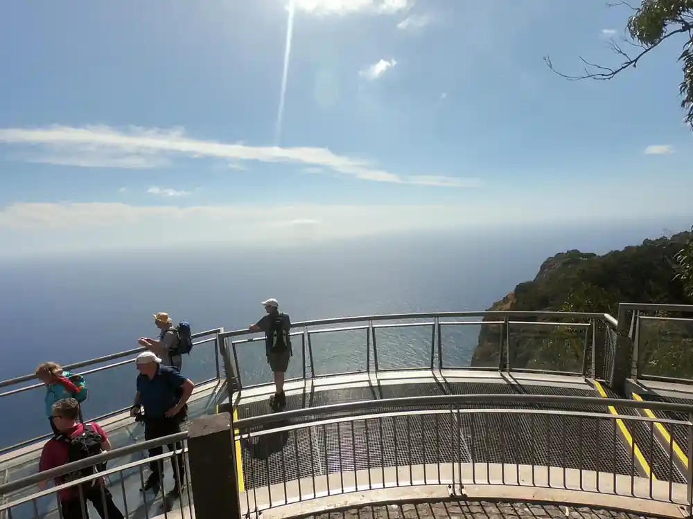 People on curved railing with distant ocean view