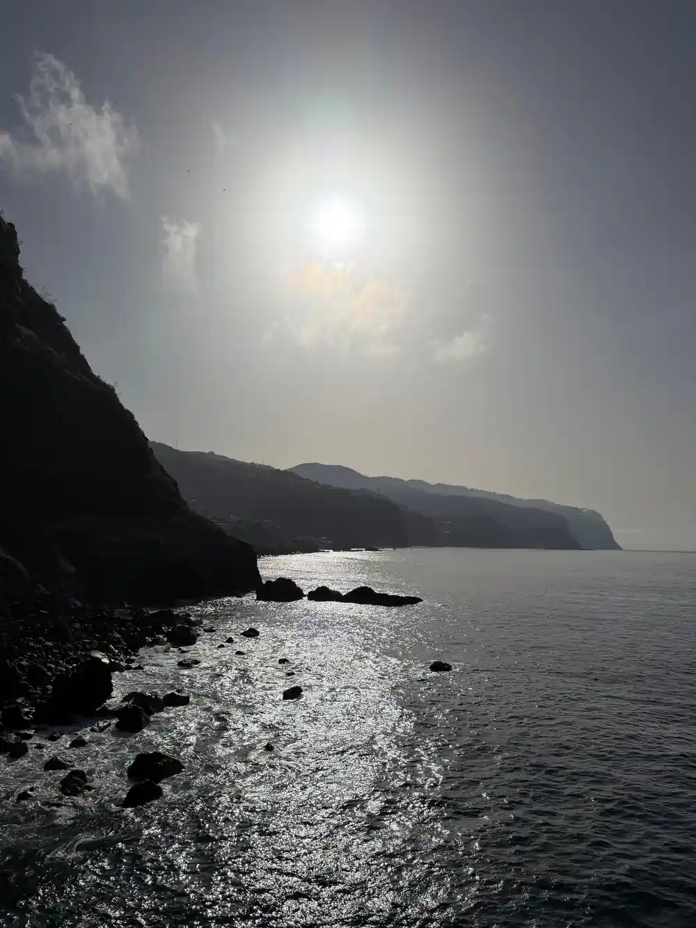 Rocky coastline with sunlit sea and distant cliffs