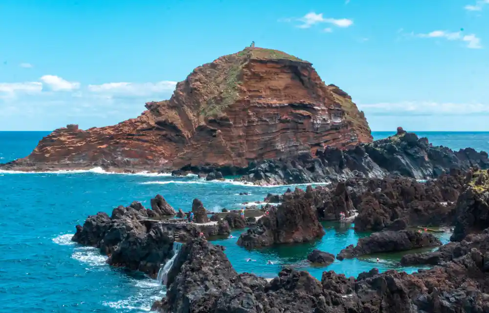 Rocky headland with turquoise water and small boats