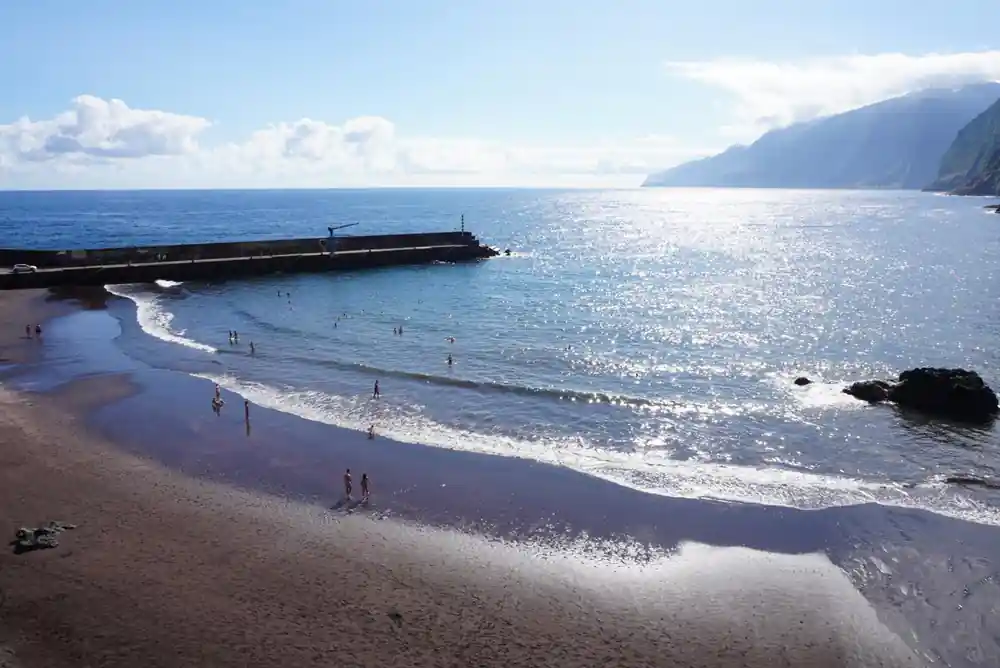 Sandy beach with cliff backdrop and swimmers