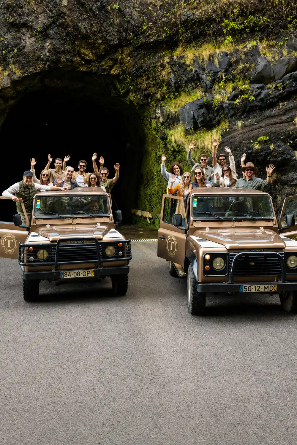 Two open-top jeeps with tourists driving through cave tunnel
