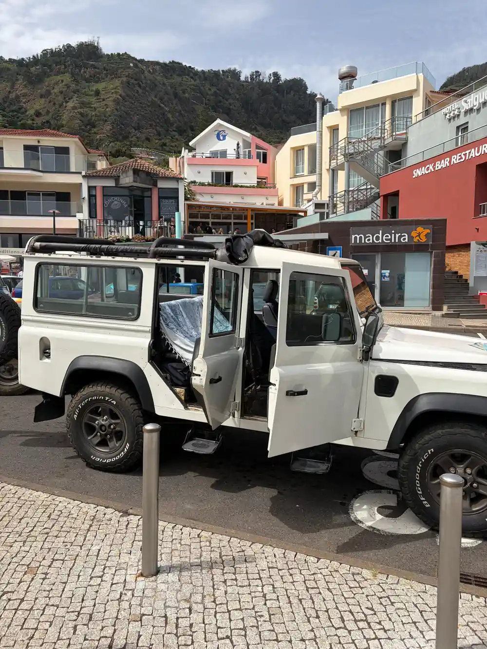 White jeep vehicle parked in village street with buildings